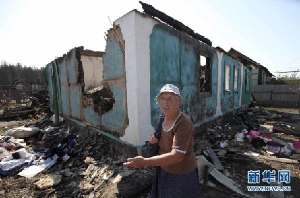 8月1日，在俄罗斯的沃罗涅日，一名妇女站在被大火烧毁的房屋前。 新华社/法新